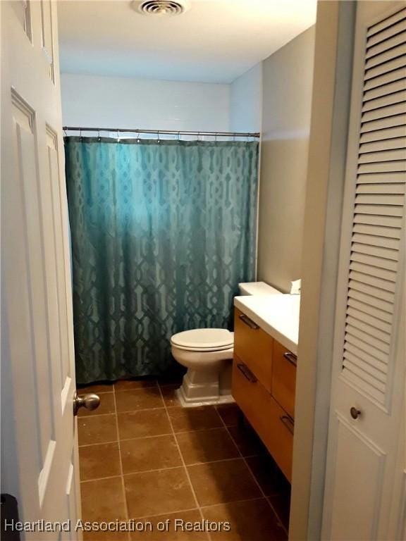 bathroom featuring walk in shower, vanity, toilet, and tile patterned flooring