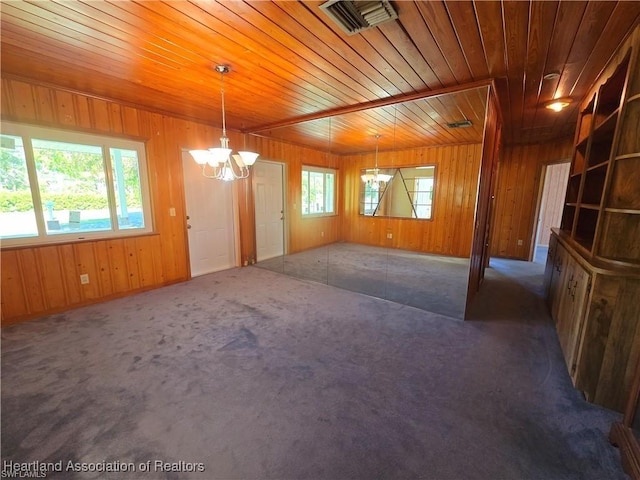 carpeted empty room with a notable chandelier and wood ceiling