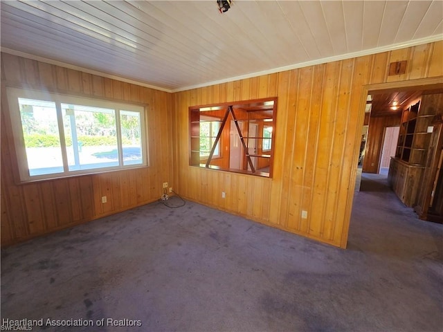 unfurnished room with crown molding, wood ceiling, dark carpet, and wooden walls