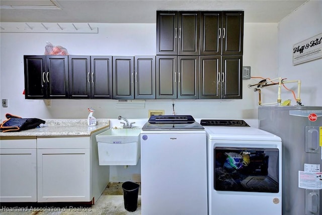 clothes washing area featuring cabinets, sink, water heater, and washing machine and clothes dryer