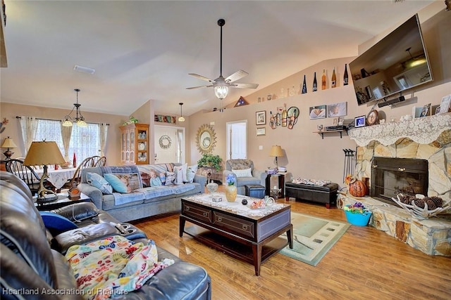 living room featuring ceiling fan, lofted ceiling, a fireplace, and light hardwood / wood-style flooring