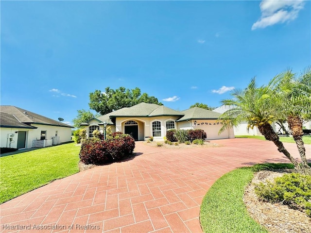 view of front facade featuring a garage, stucco siding, a front yard, and decorative driveway