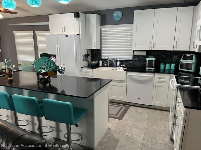 1570 Spring Ln, Lake Placid, FL 33852 - kitchen with white appliances, a sink, dark countertops, decorative backsplash, and white cabinetry