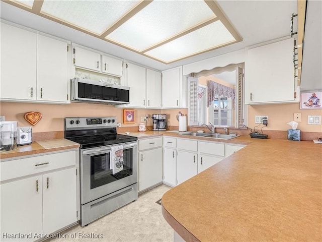 kitchen with stainless steel appliances, light countertops, white cabinetry, and a sink