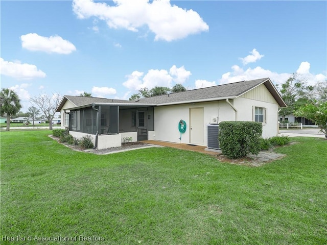 rear view of house with cooling unit, a sunroom, and a yard