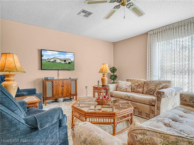 living room with a textured ceiling, ceiling fan, and visible vents