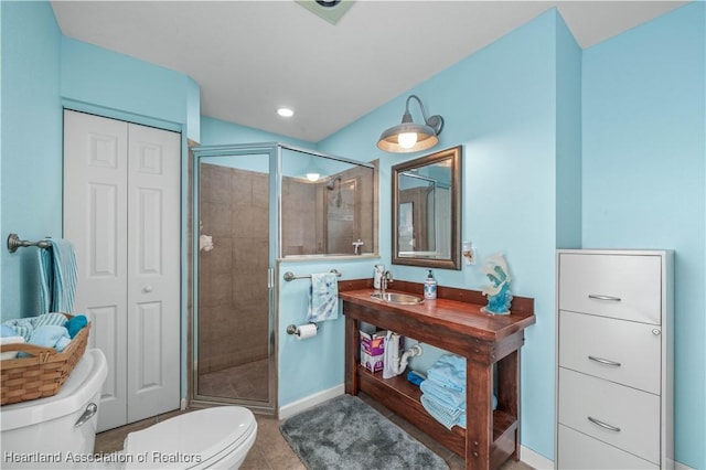 bathroom featuring tile patterned floors, toilet, a shower with door, and sink