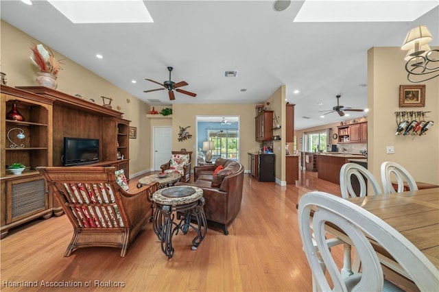 living room featuring light hardwood / wood-style flooring, a skylight, and ceiling fan