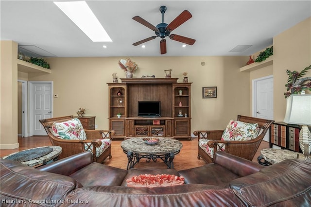 living room featuring hardwood / wood-style floors, a skylight, and ceiling fan