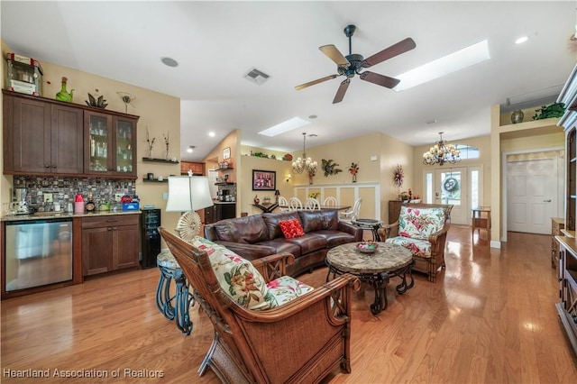 living room featuring ceiling fan with notable chandelier, bar area, and light hardwood / wood-style floors