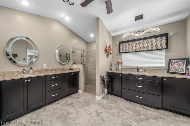 bathroom with vaulted ceiling, tiled shower, vanity, and ceiling fan