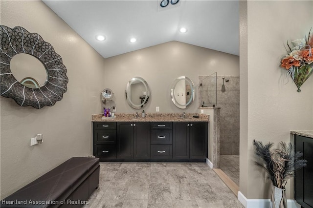 bathroom featuring vaulted ceiling, tiled shower, and vanity