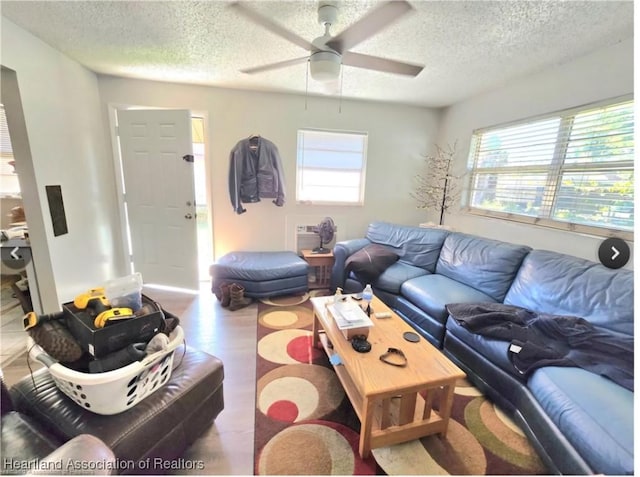 living room with ceiling fan, a textured ceiling, and a wealth of natural light