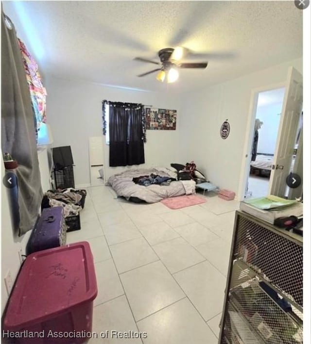 bedroom featuring ceiling fan, a textured ceiling, and light tile patterned flooring