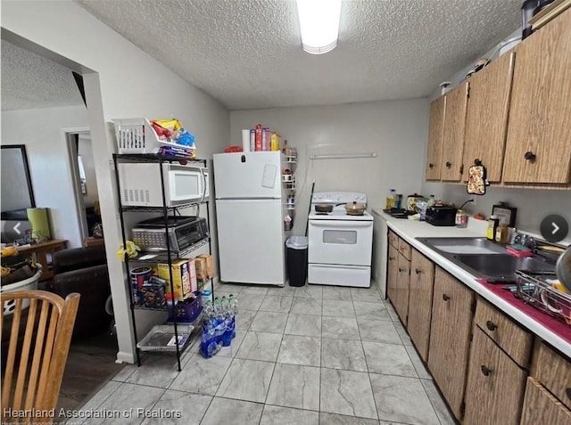 kitchen featuring sink, white appliances, and a textured ceiling