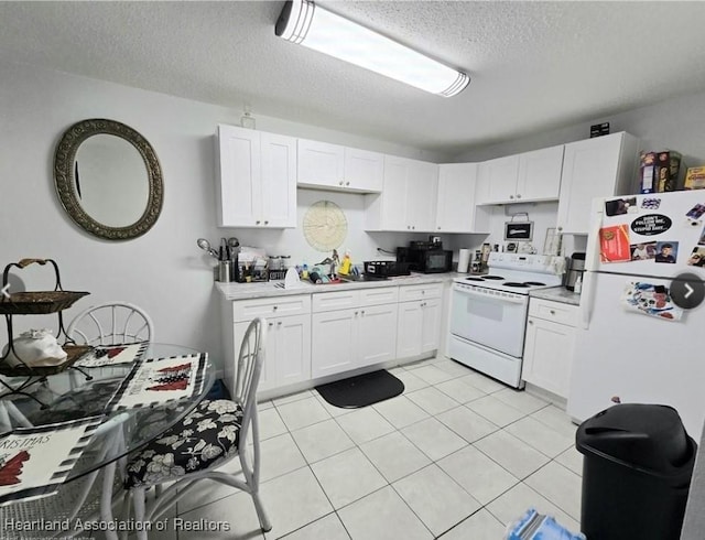 kitchen featuring a textured ceiling, light tile patterned floors, white cabinets, and white appliances