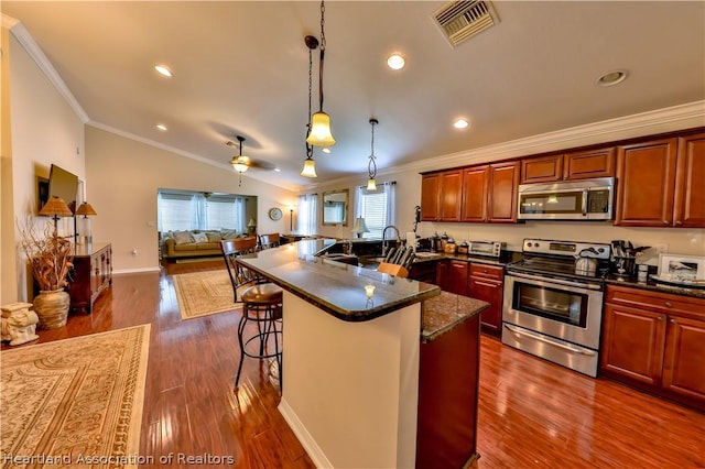 kitchen featuring stainless steel appliances, vaulted ceiling, ceiling fan, hanging light fixtures, and a breakfast bar area