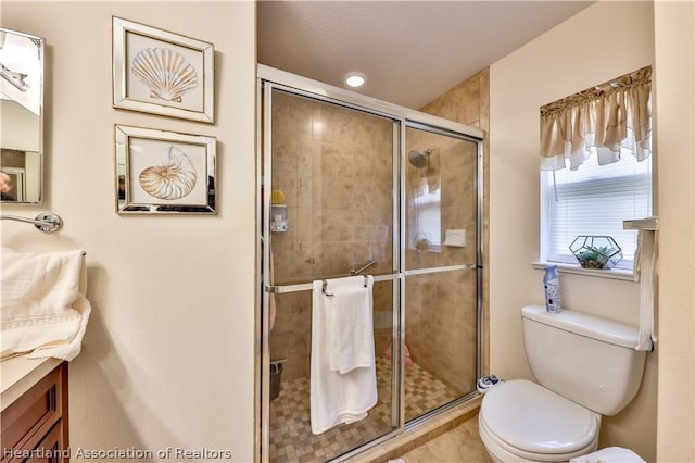 bathroom featuring vanity, toilet, and a shower with door