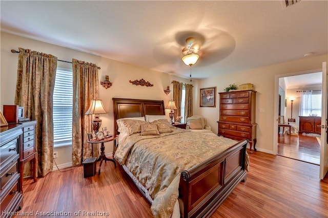 bedroom with hardwood / wood-style floors, ceiling fan, and multiple windows