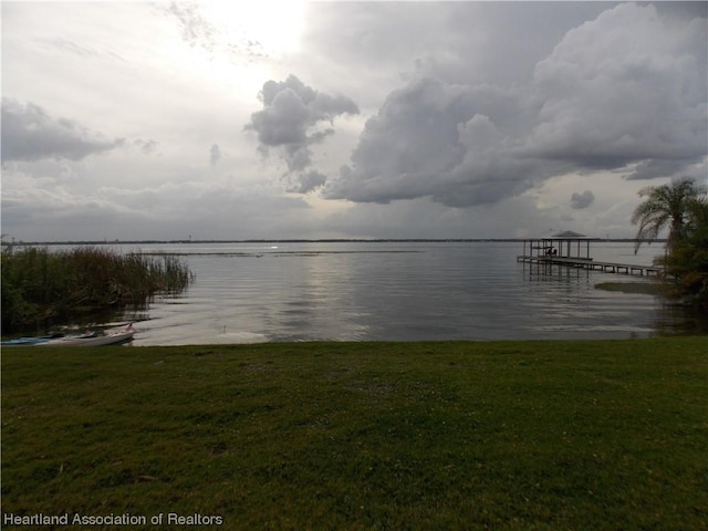 view of dock featuring a lawn and a water view