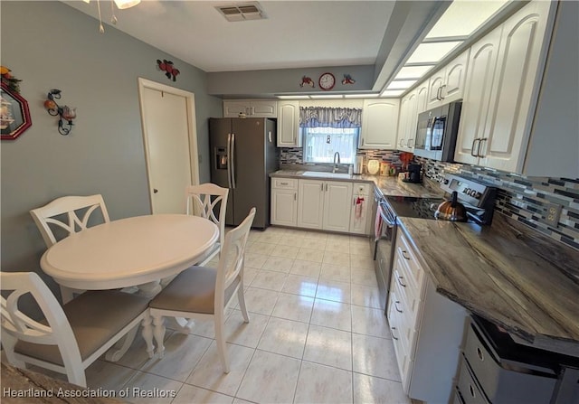 kitchen featuring stainless steel appliances, sink, light tile patterned floors, and backsplash