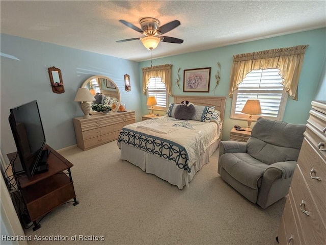 bedroom with ceiling fan, light carpet, and a textured ceiling