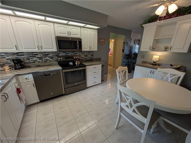 kitchen featuring tasteful backsplash, stainless steel appliances, light tile patterned floors, and white cabinets