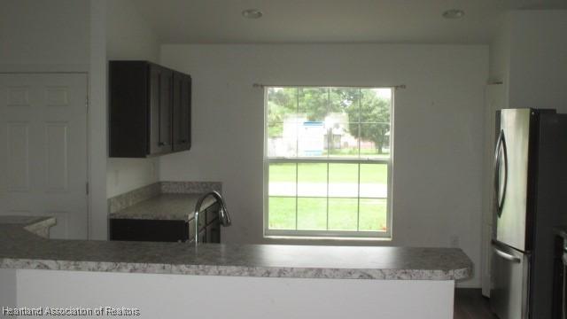 kitchen featuring plenty of natural light, kitchen peninsula, sink, and stainless steel refrigerator