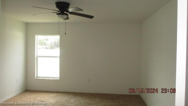 empty room featuring ceiling fan and light colored carpet