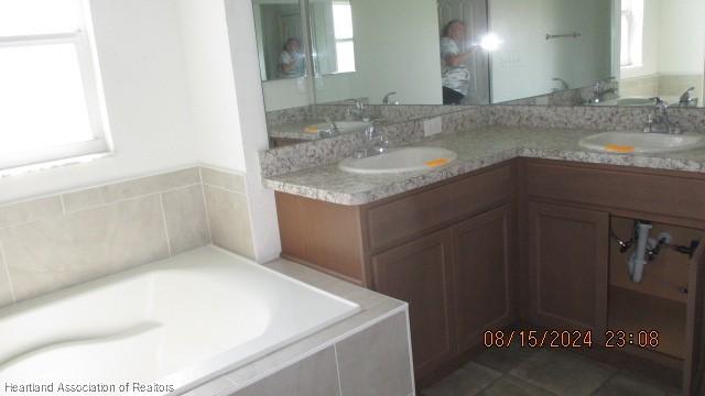 bathroom with vanity, tiled bath, and plenty of natural light