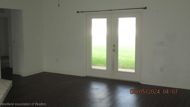 spare room with french doors, dark hardwood / wood-style flooring, and a wealth of natural light