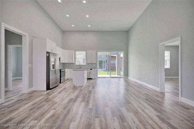 2545 N Odessa Rd, Avon Park, FL 33825 - unfurnished living room with a towering ceiling, a sink, baseboards, recessed lighting, and light wood-style floors