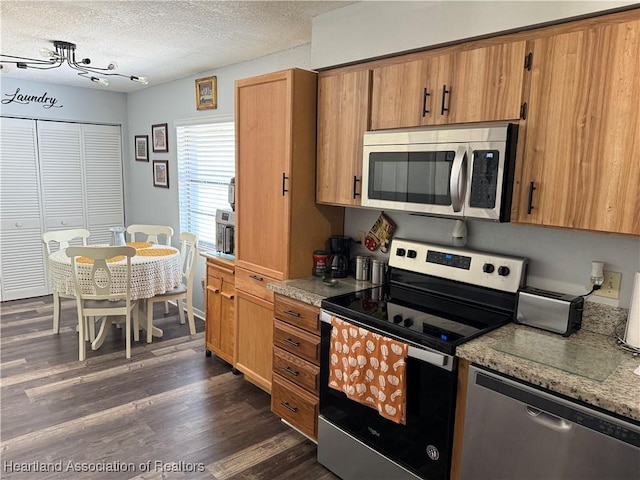 103 Fox Rd, Lake Placid, FL 33852 - kitchen with brown cabinetry, appliances with stainless steel finishes, a textured ceiling, and dark wood-type flooring