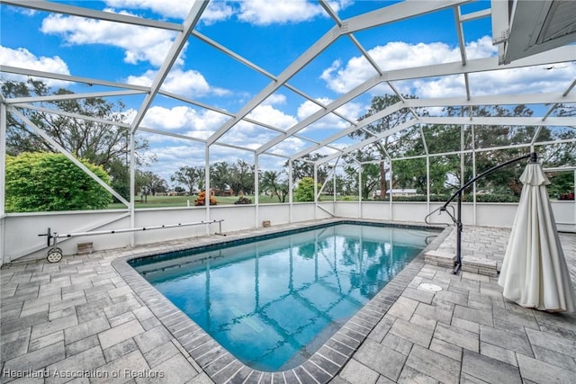 view of swimming pool with glass enclosure and a patio