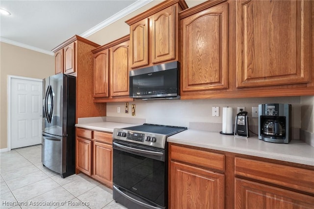 kitchen with light tile patterned floors, ornamental molding, and appliances with stainless steel finishes