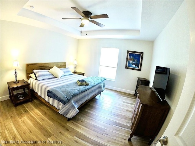 6978 Mexican Hat Dr, Sebring, FL 33872 - bedroom with a raised ceiling, light wood-style floors, and a ceiling fan