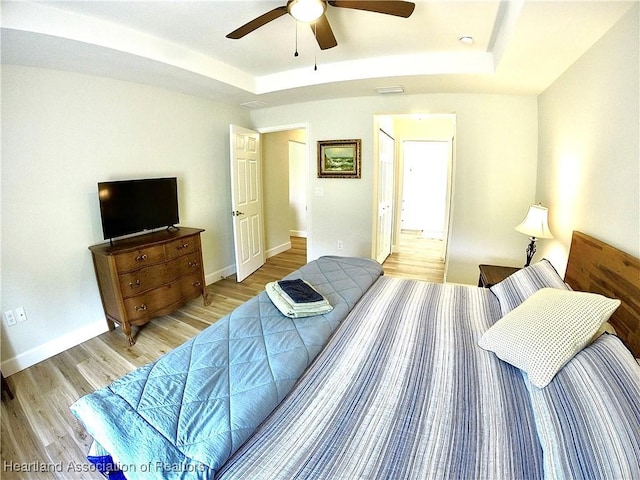 6978 Mexican Hat Dr, Sebring, FL 33872 - bedroom with a raised ceiling, light wood-style floors, ceiling fan, and ensuite bathroom