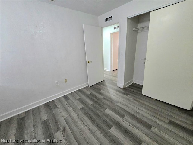 unfurnished bedroom featuring dark hardwood / wood-style flooring and a closet