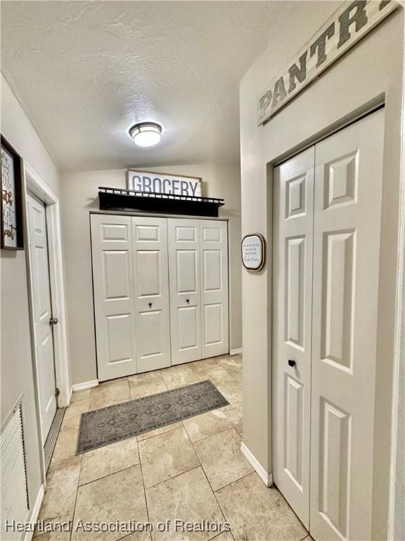 interior space featuring visible vents, a textured ceiling, and baseboards