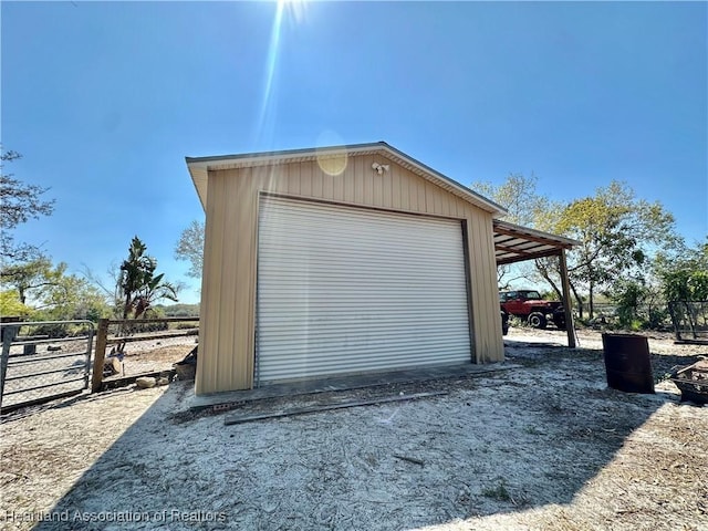 garage featuring driveway, a detached garage, and fence