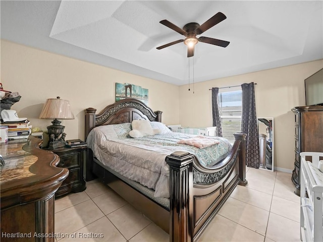 tiled bedroom featuring ceiling fan and a tray ceiling