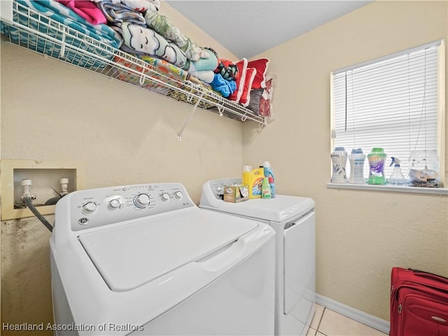 clothes washing area featuring washer and clothes dryer and light tile patterned floors