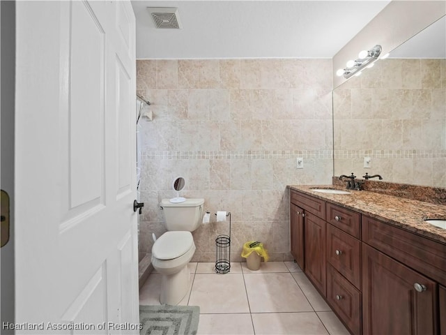 bathroom with tile walls, toilet, vanity, and tile patterned flooring