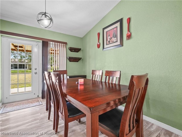 dining area with plenty of natural light, light hardwood / wood-style flooring, and vaulted ceiling