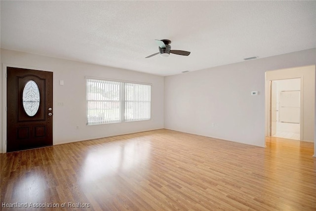 foyer entrance with a textured ceiling, light wood-type flooring, and ceiling fan