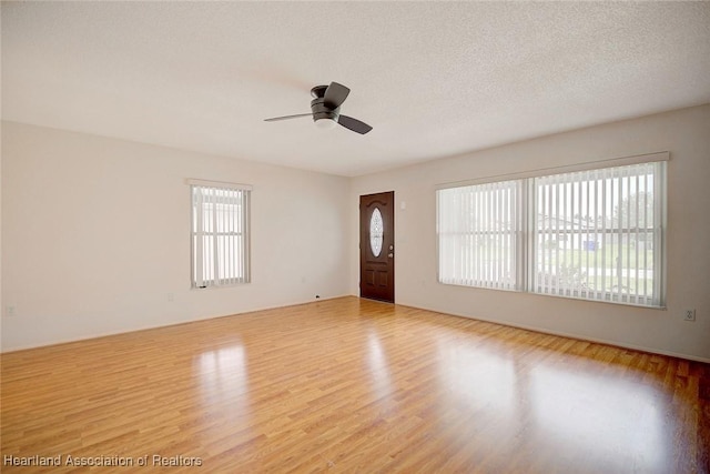 spare room featuring ceiling fan, light hardwood / wood-style floors, and a textured ceiling