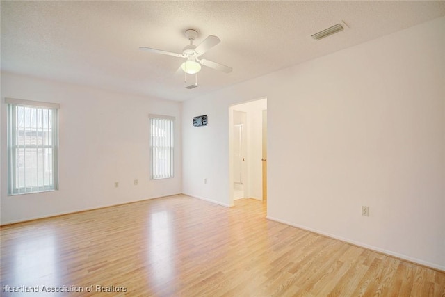 unfurnished room with ceiling fan, a textured ceiling, and light wood-type flooring