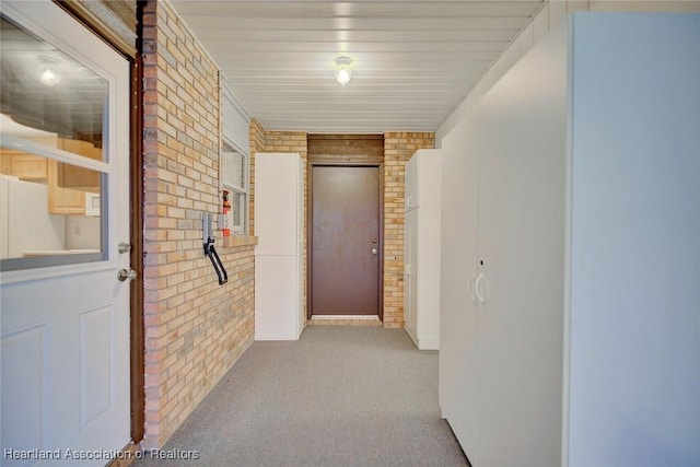 hall with light carpet and brick wall