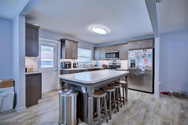 kitchen with a breakfast bar, sink, light hardwood / wood-style flooring, appliances with stainless steel finishes, and a kitchen island