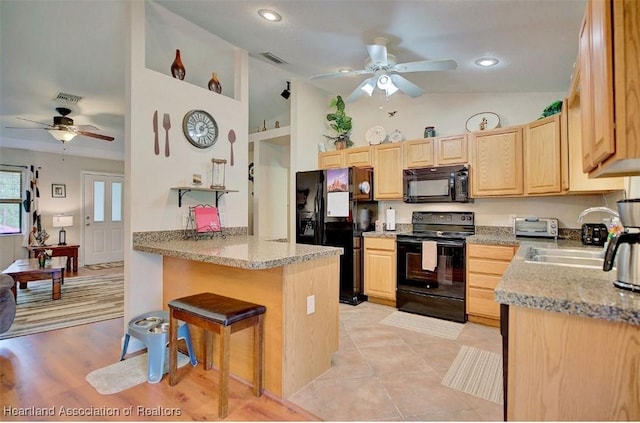 kitchen featuring a breakfast bar, light brown cabinets, black appliances, sink, and kitchen peninsula